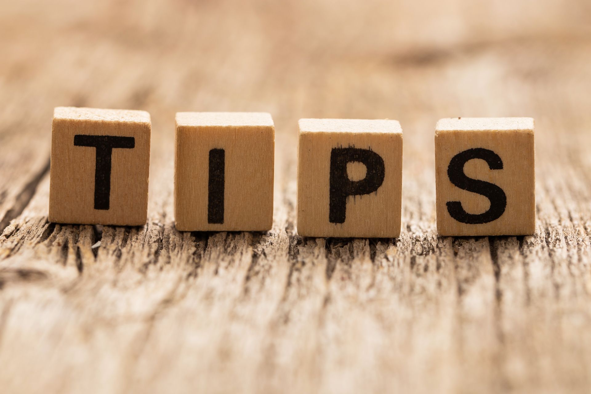 The word tips is written on wooden blocks on a wooden table.