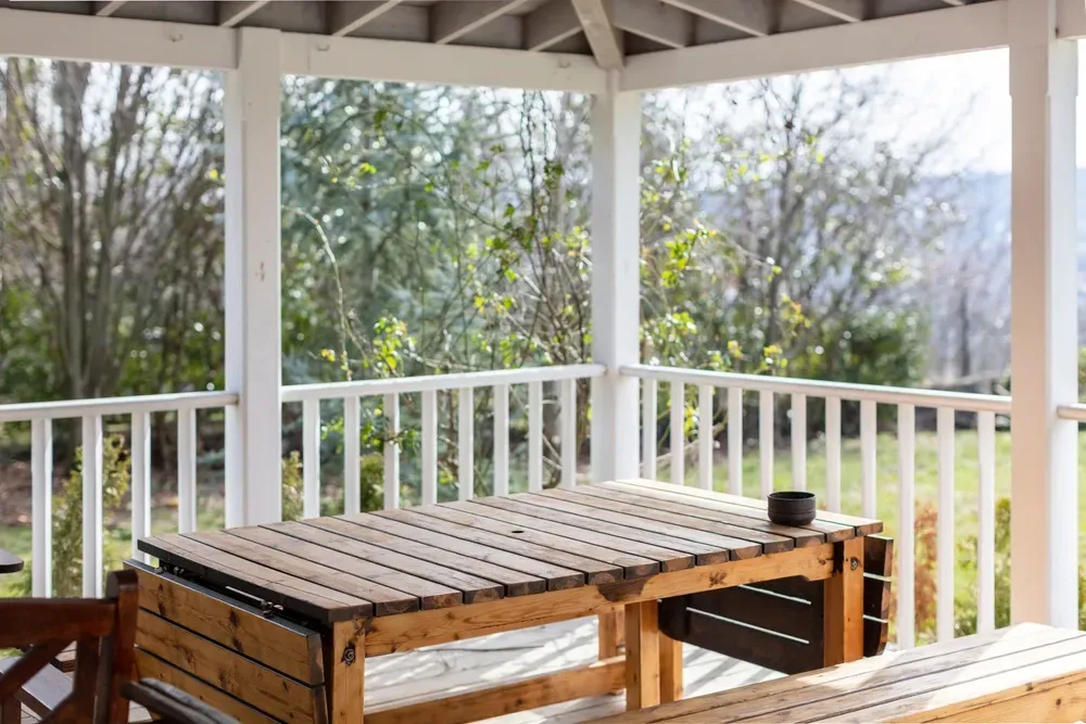 Wooden table and benches on a porch, overlooking a green yard and trees. — Dimond J Carpentry in Bli Bli, QLD