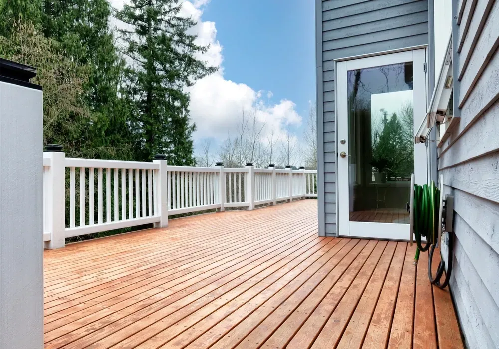 Wooden deck with white railing, glass door to gray house, blue sky with clouds. — Dimond J Carpentry in Bli Bli, QLD