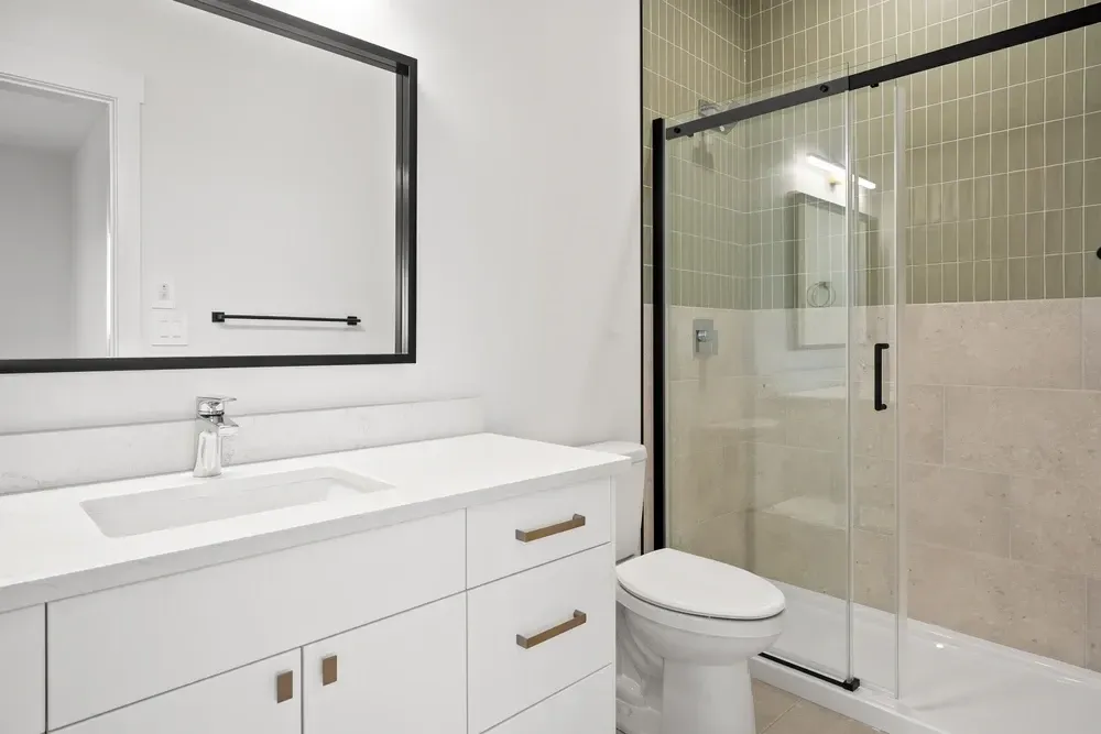Modern bathroom with white vanity, toilet, and glass shower with black trim. — Dimond J Carpentry in Bli Bli, QLD