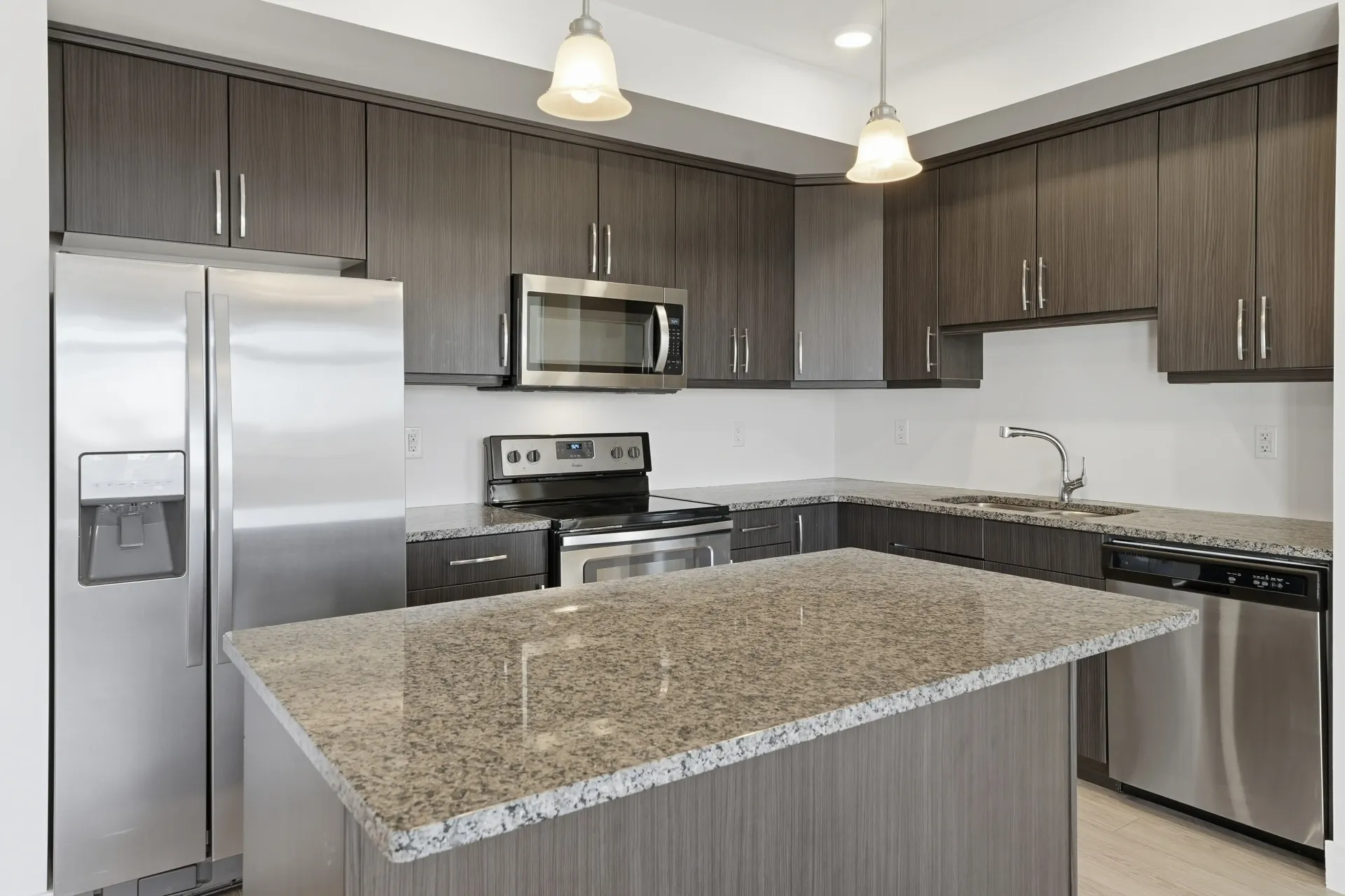 Modern kitchen with gray cabinets, stainless steel appliances, and granite countertops.