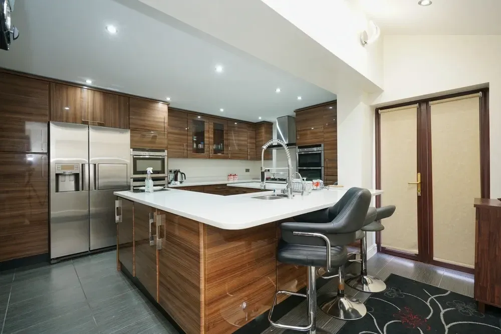 Modern kitchen with wood cabinets, stainless steel appliances, island with seating, and frosted glass doors. — Dimond J Carpentry in Bli Bli, QLD