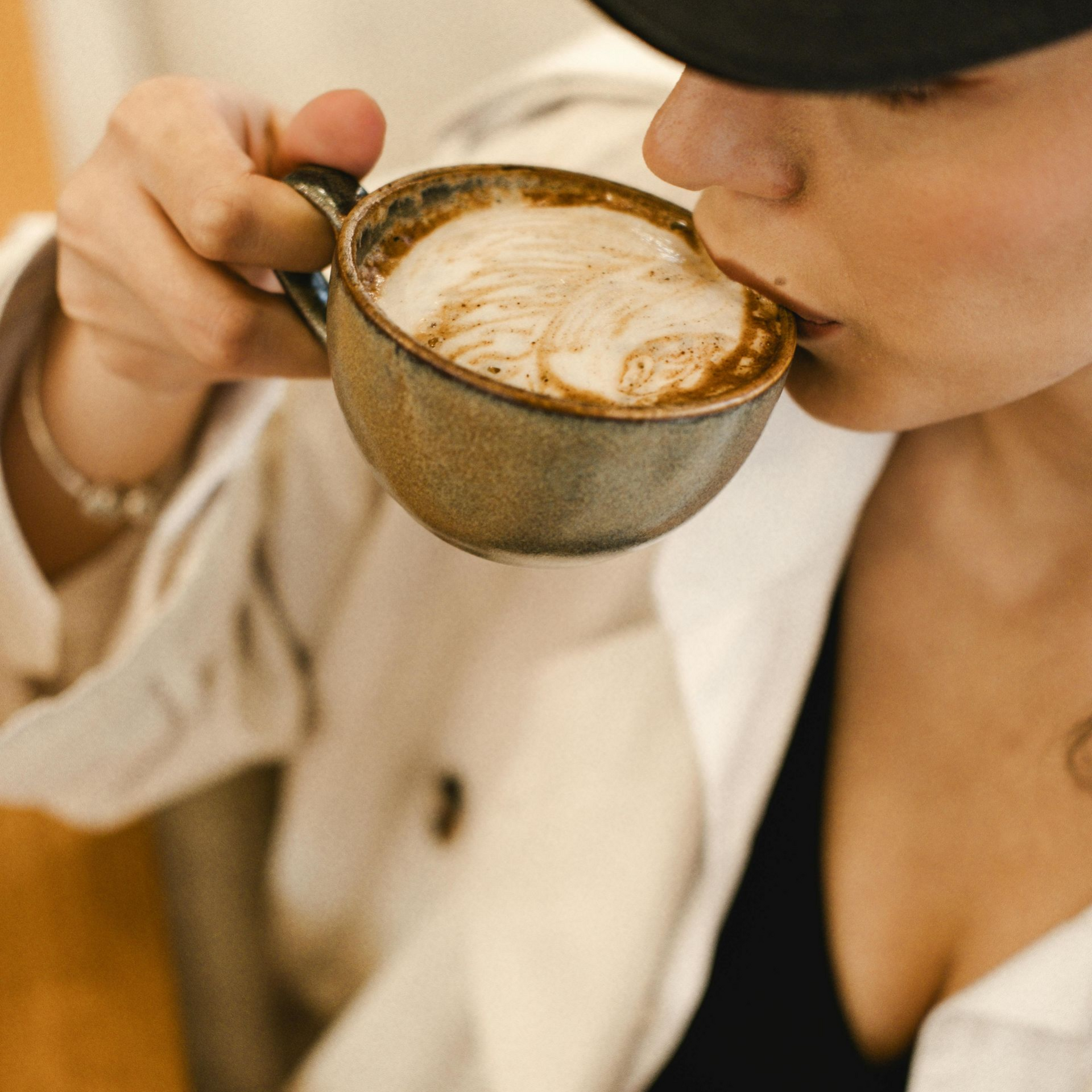 Kopje latte met latte art op een schoteltje en een lepel.