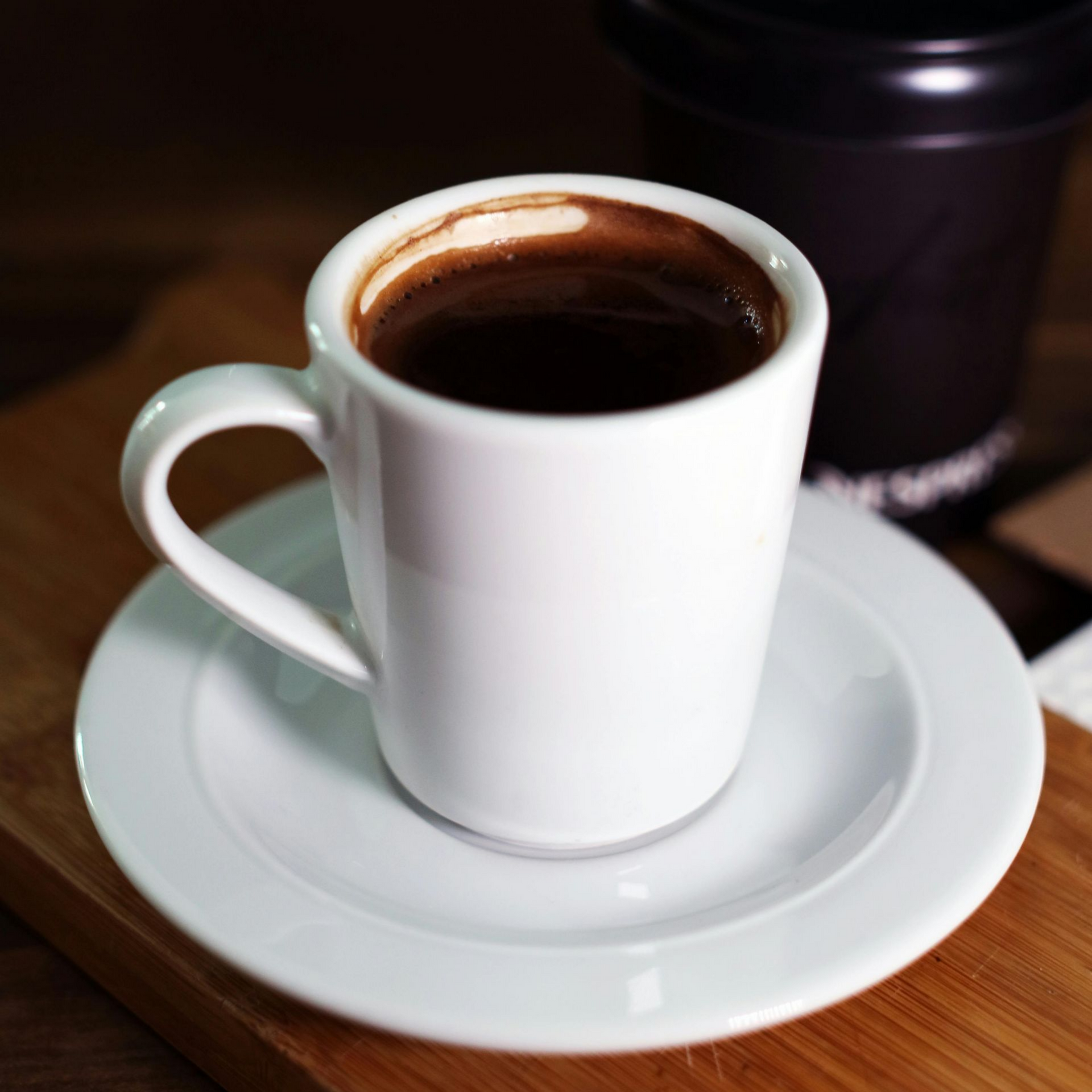 Kopje latte met latte art op een schoteltje en een lepel. 