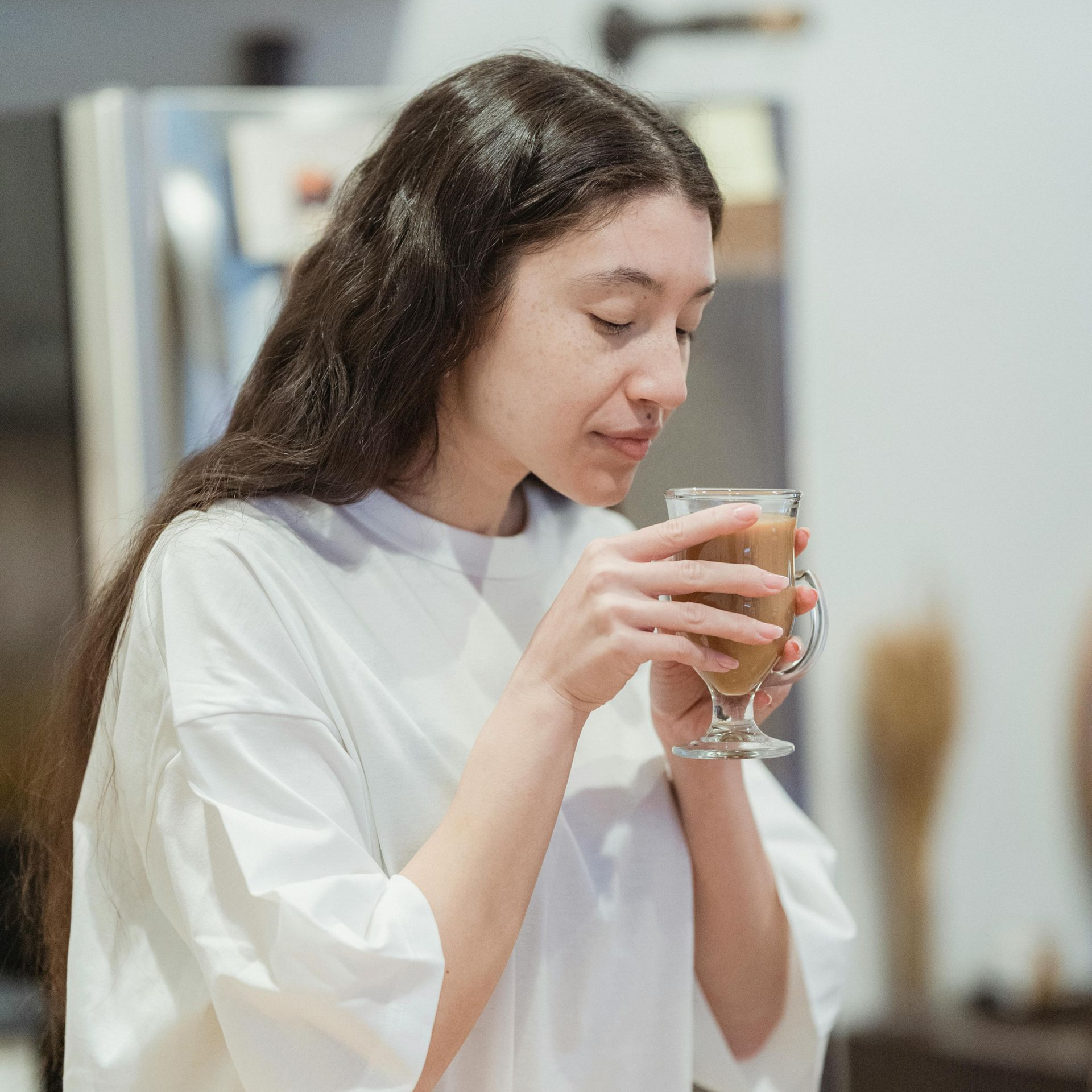 Groene vallei met bomen, huizen en met sneeuw bedekte bergen onder een stralendblauwe lucht.