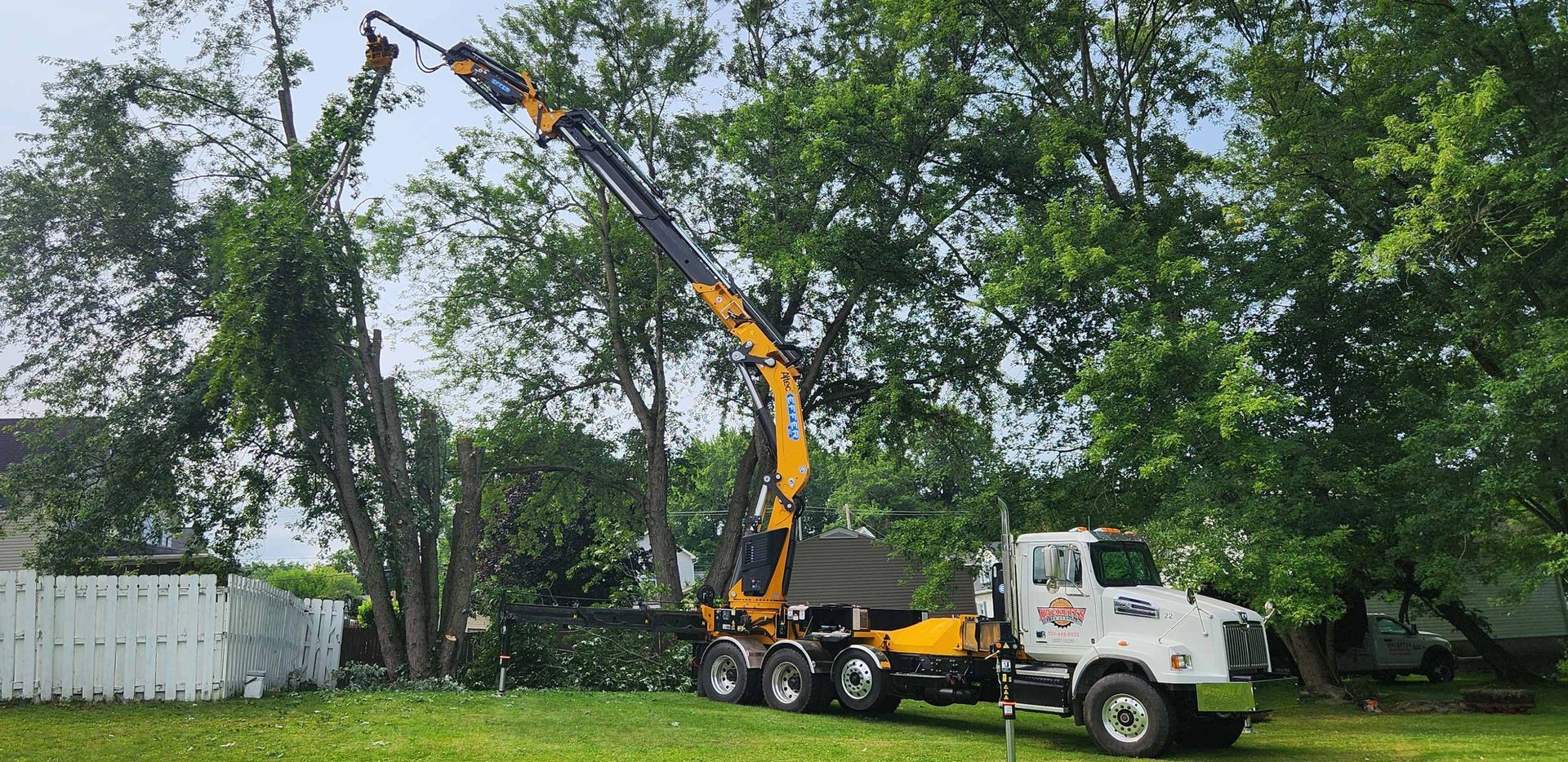 Truck With a Crane Attached to It is Cutting a Tree — Masury, OH — Hackett's Tree Service