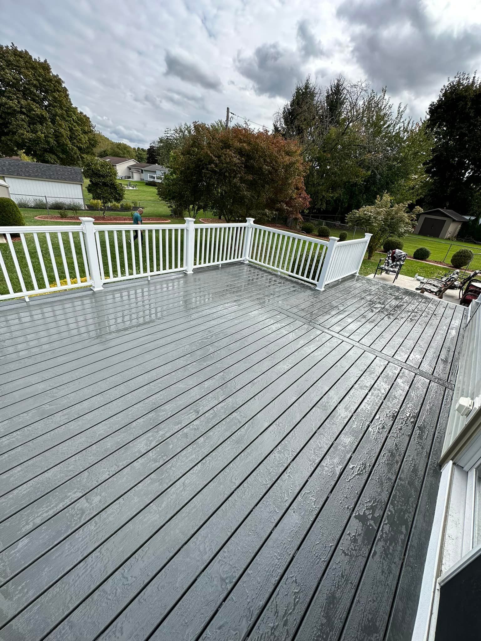 A white deck with a white railing is in front of a house.