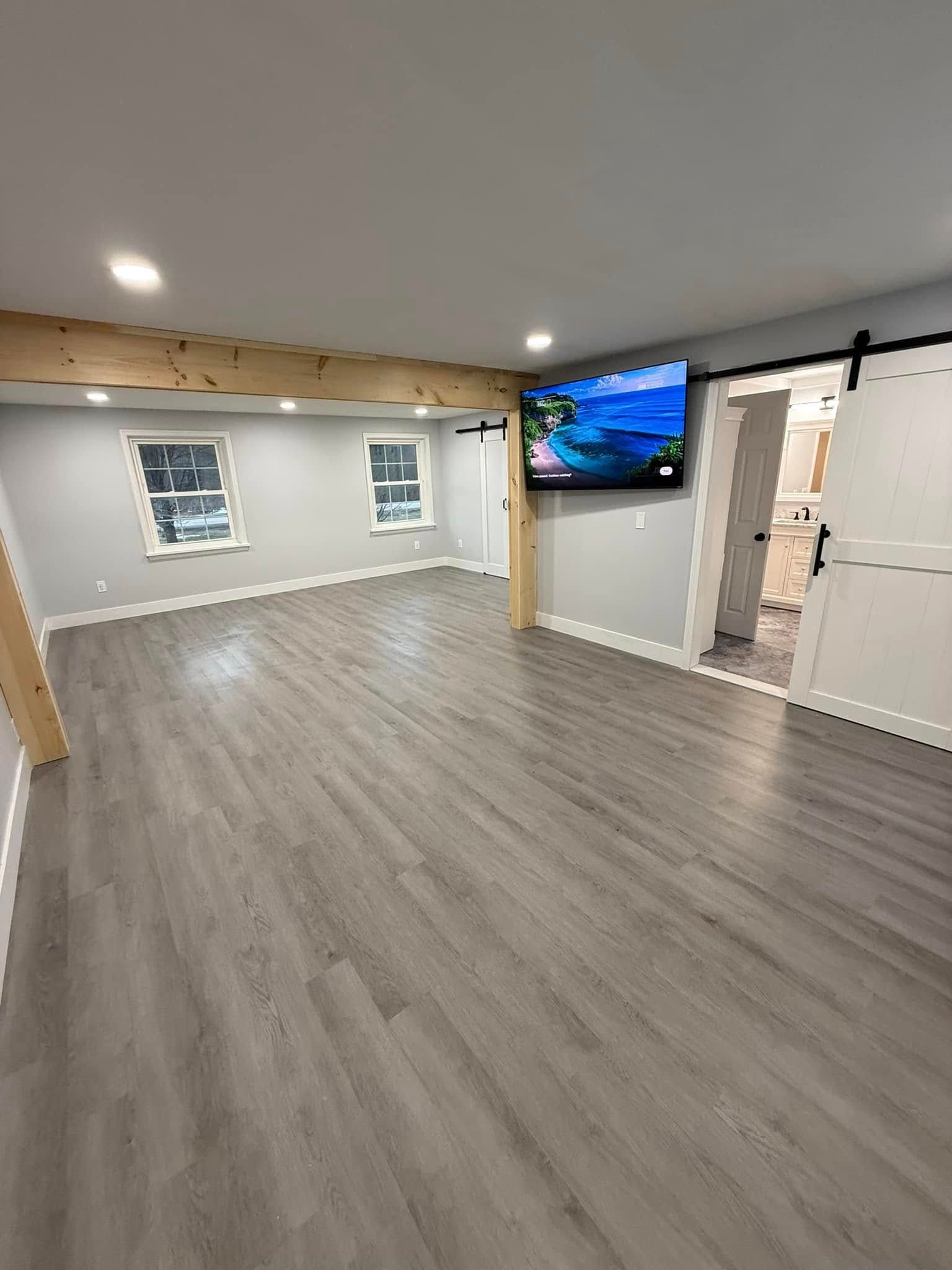 A bathroom with a sliding barn door and a flat screen tv on the wall.