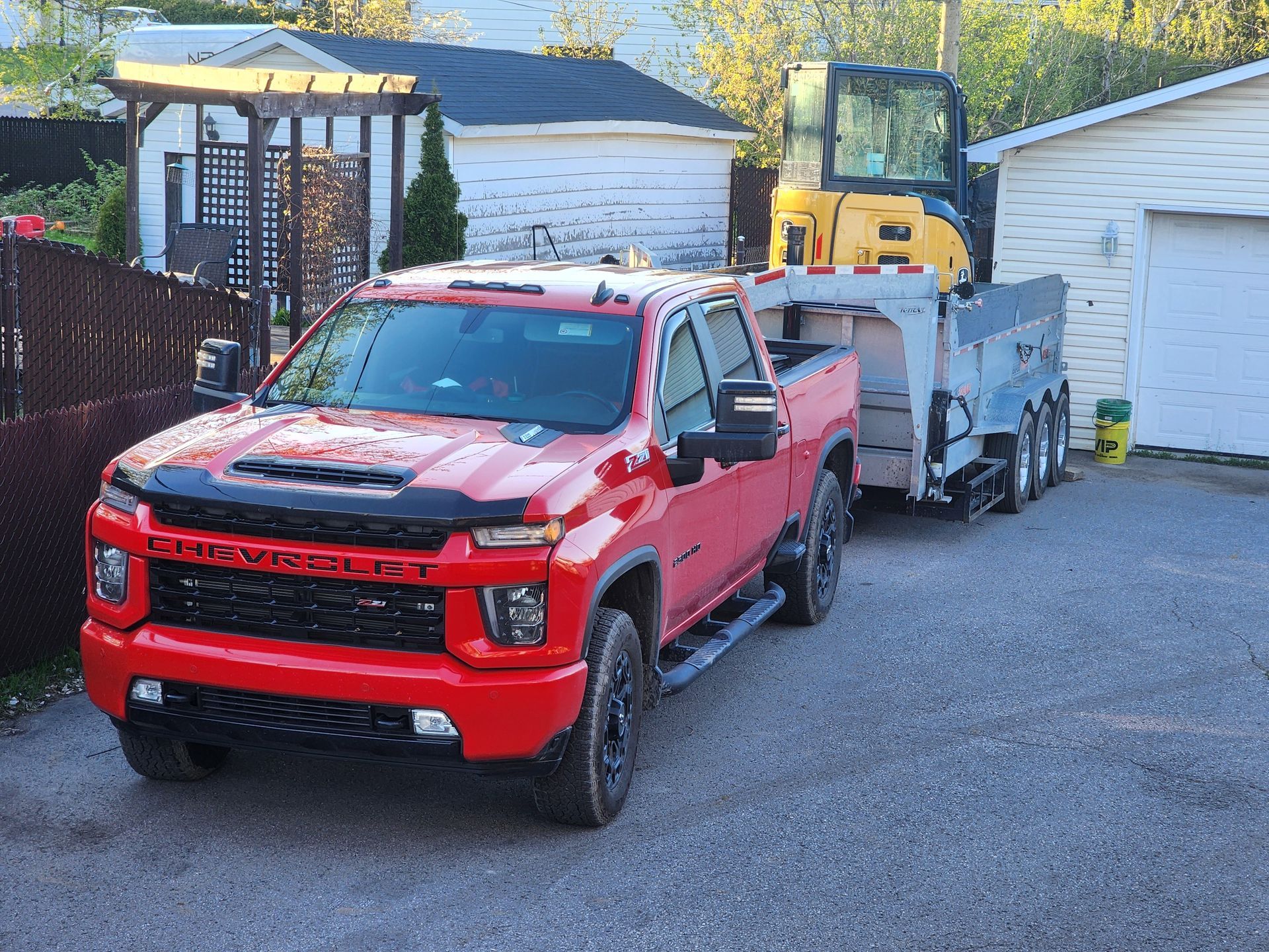 Un camion rouge remorque une excavatrice jaune sur une remorque.