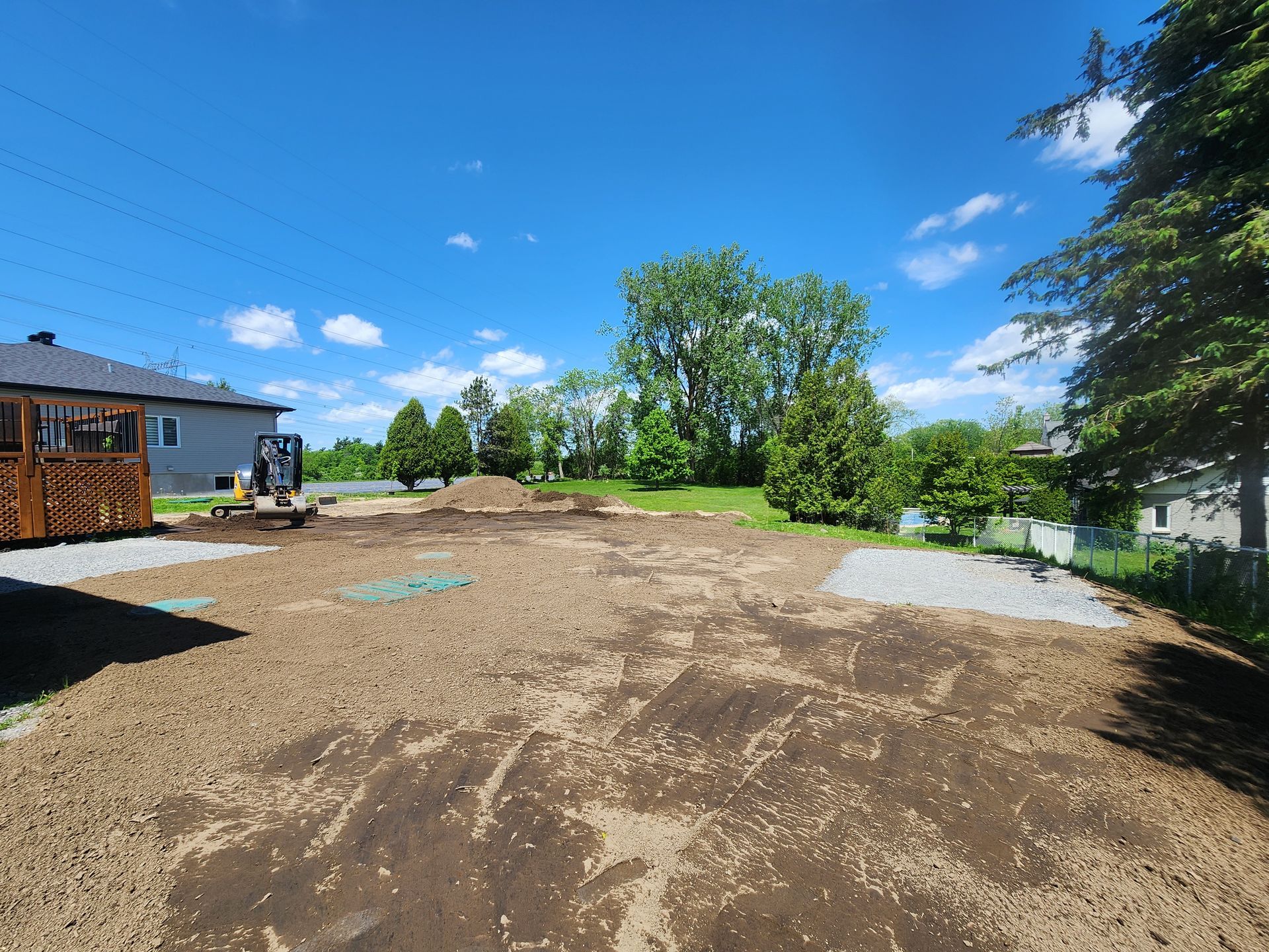 Un grand champ de terre avec une maison en arrière-plan.