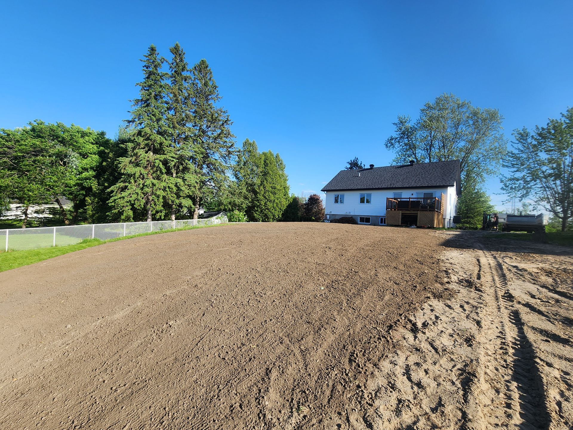 Une maison blanche se trouve au milieu d'un champ de terre