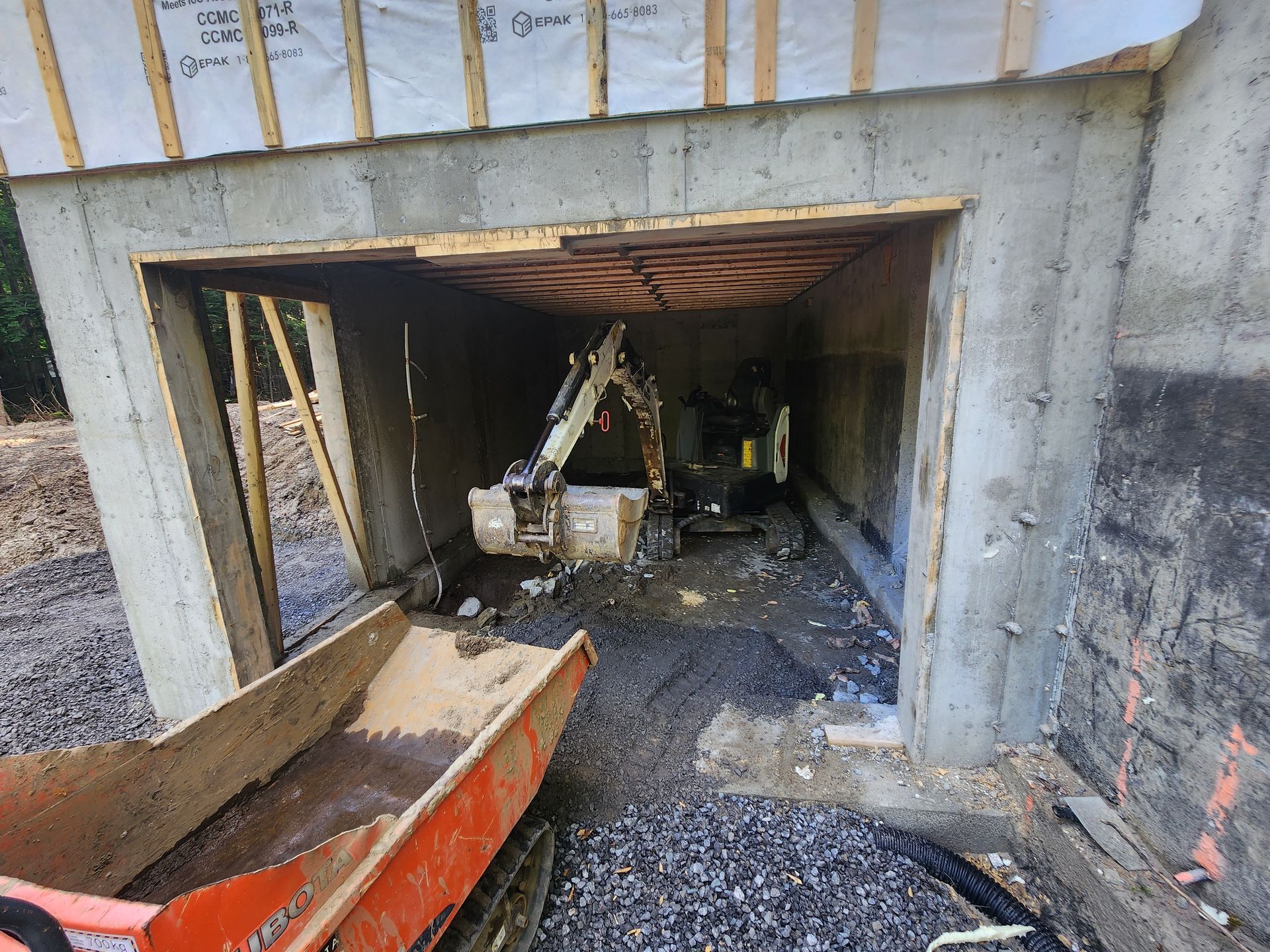 Une excavatrice est assise à l'intérieur d'un garage en construction.