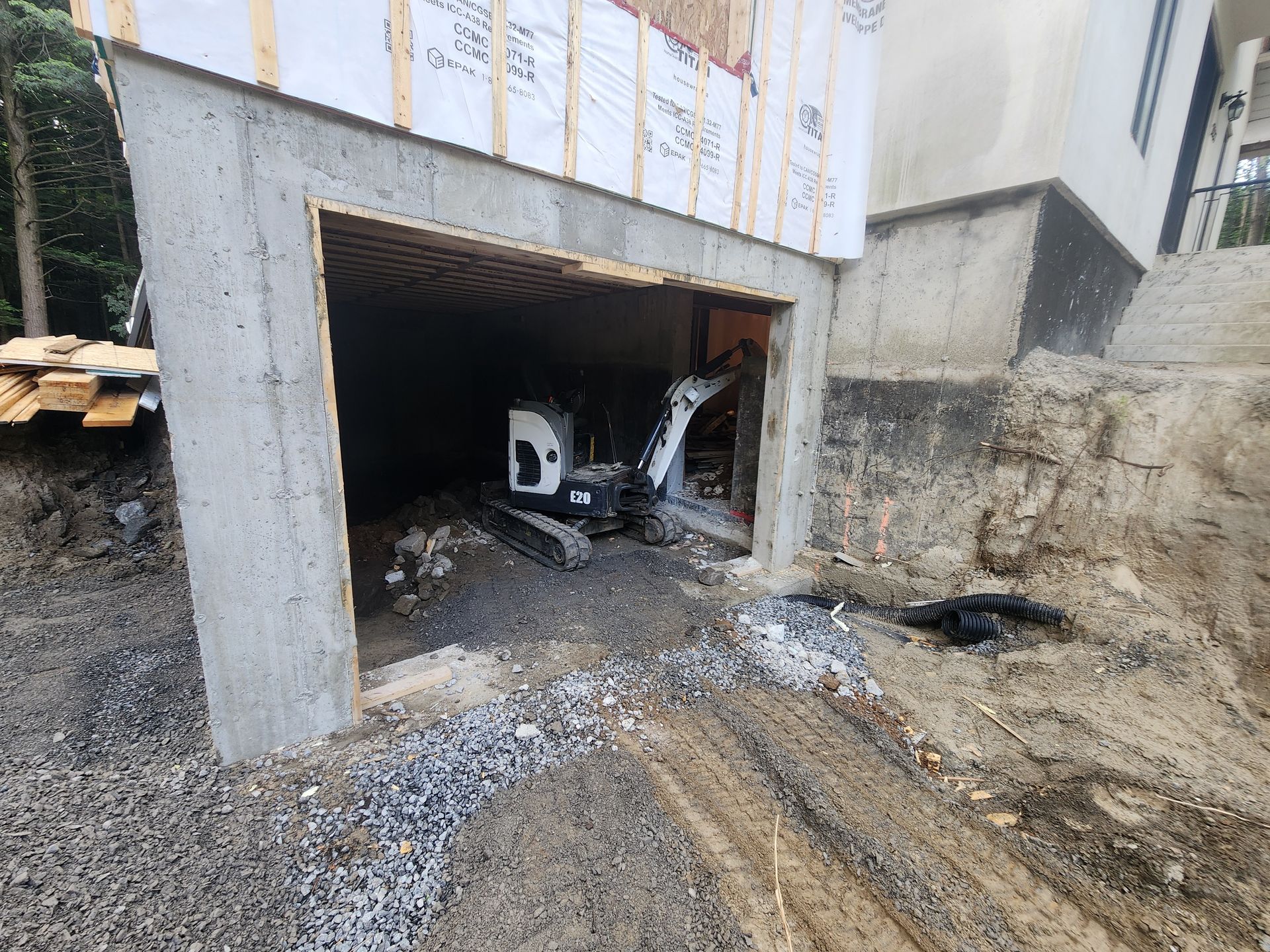 Une petite excavatrice est assise à l'intérieur d'un garage en construction.