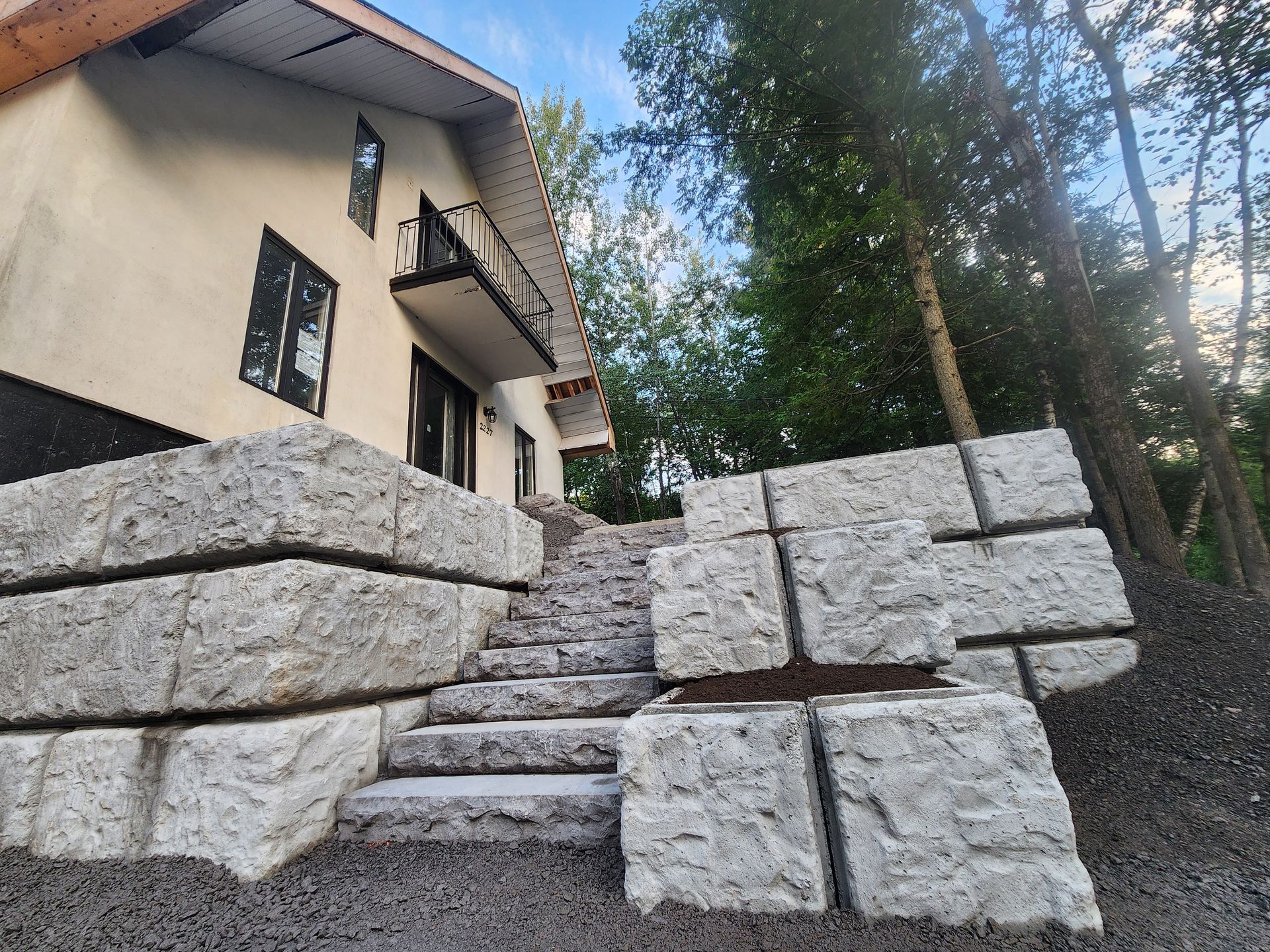 Une maison avec un mur en pierre et des escaliers qui y mènent.