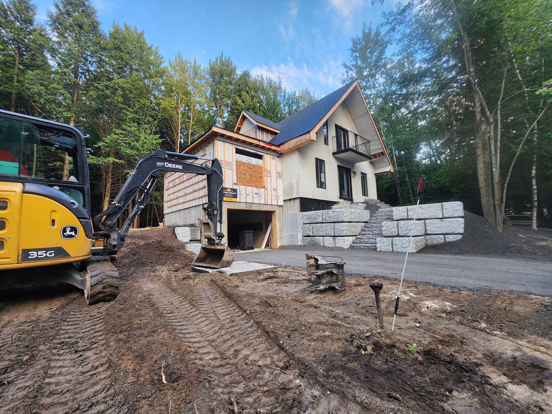 Un bulldozer déplace de la terre devant une maison en construction.