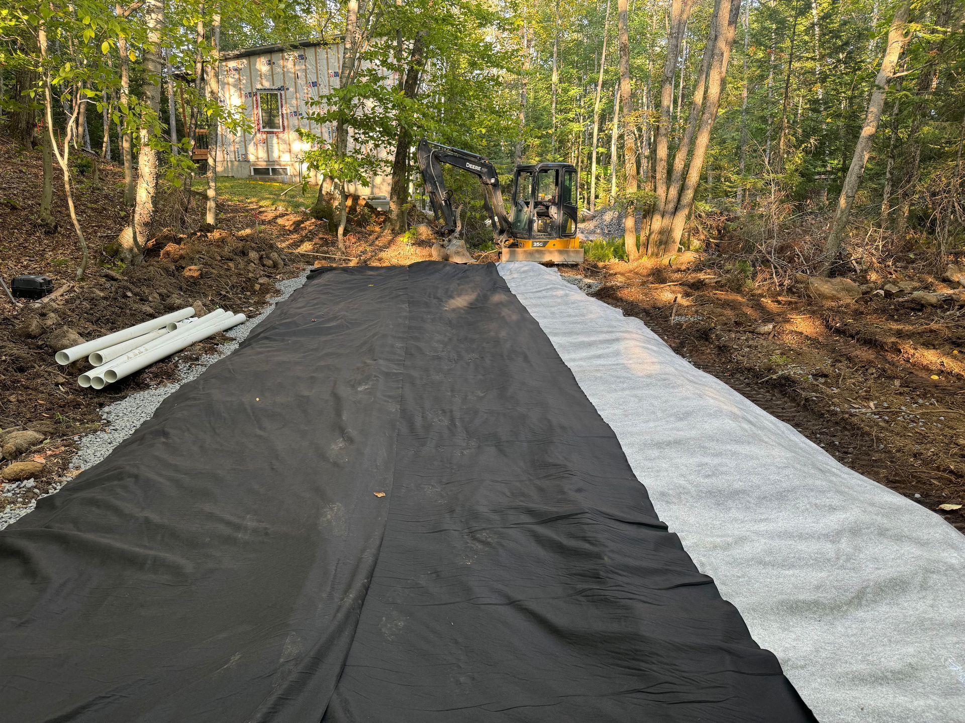 Une bâche noire et blanche recouvre une route dans les bois.