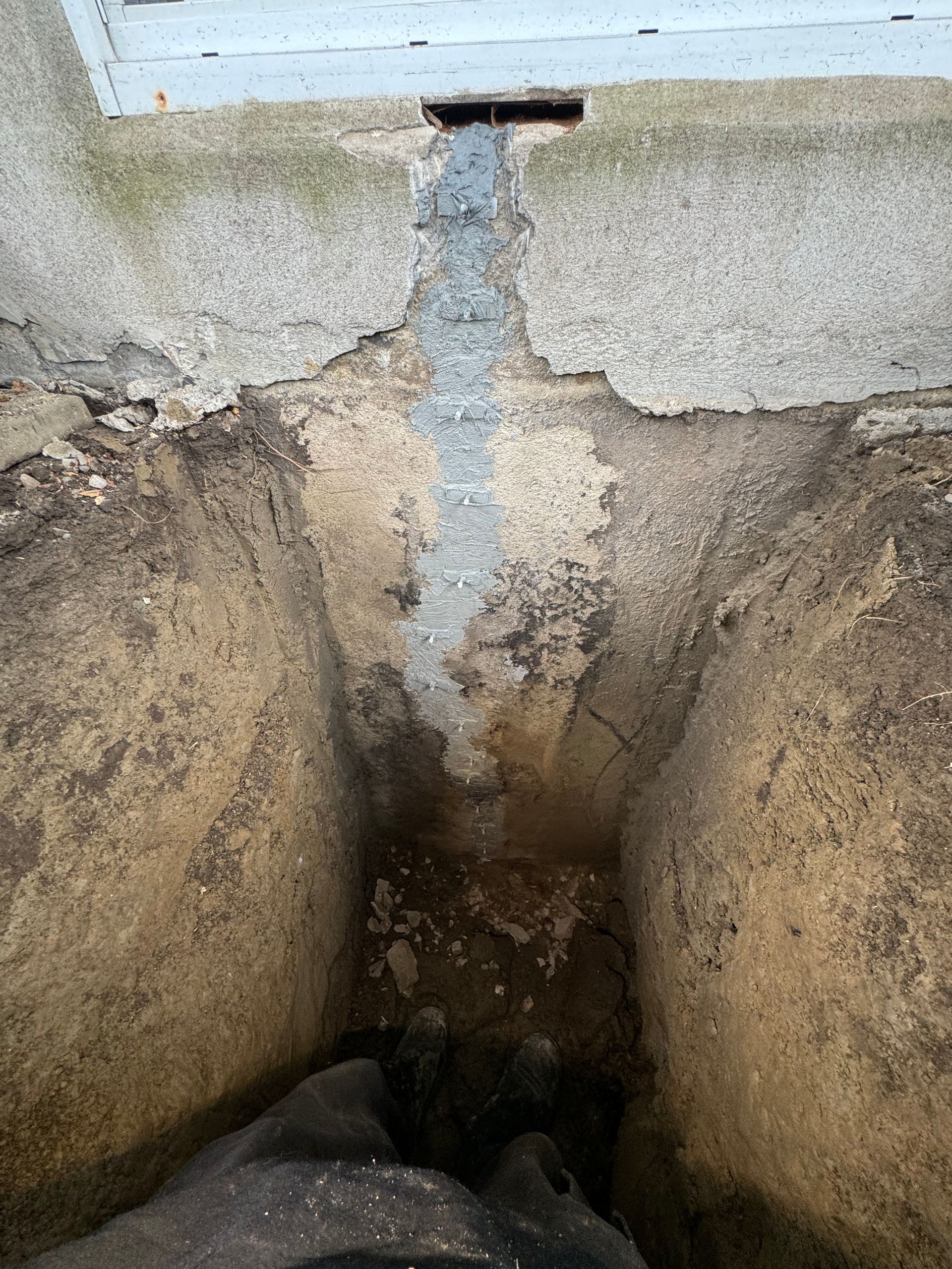 Une personne se tient dans un trou dans le sol à côté d'une fenêtre.