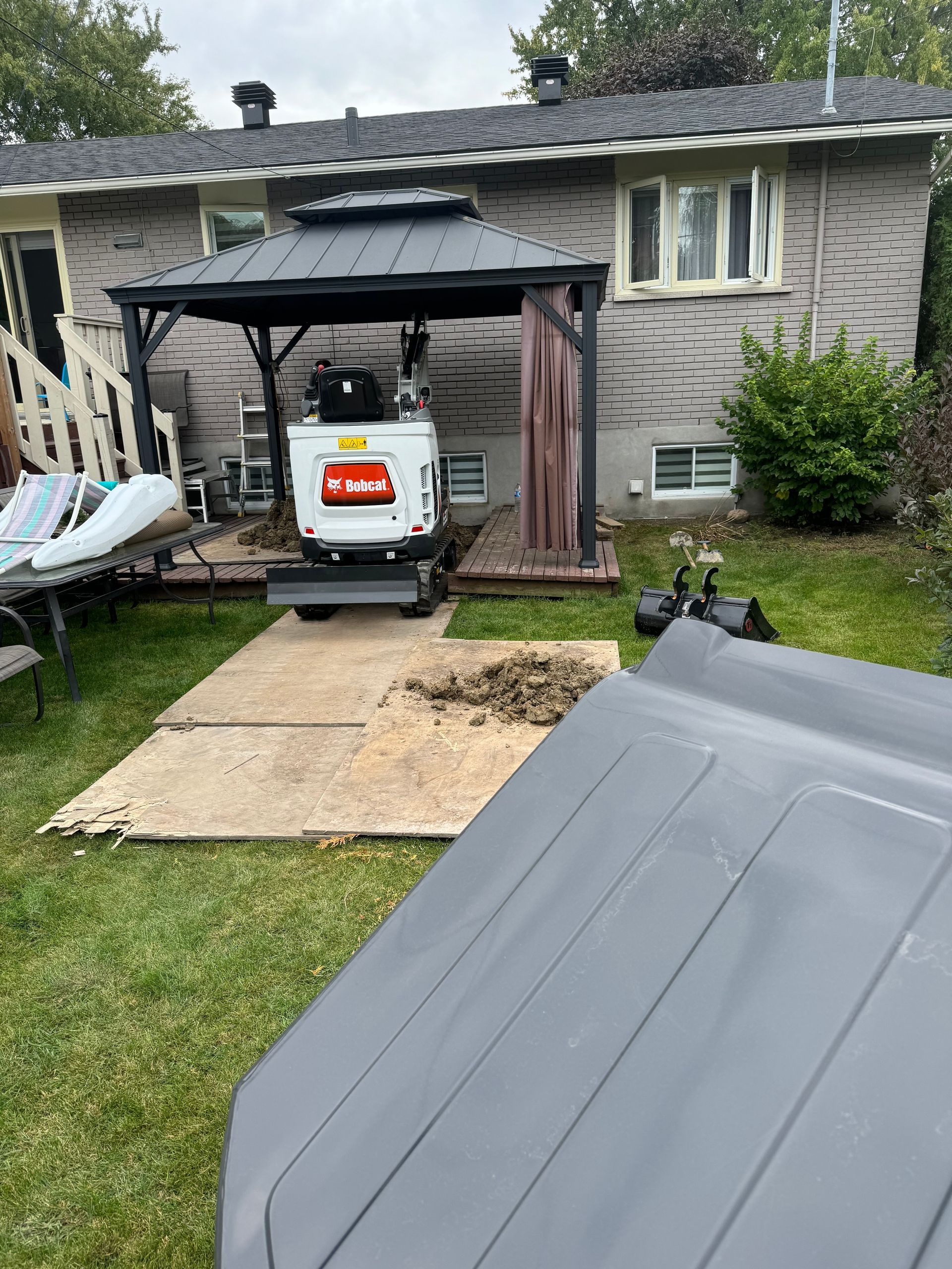 Une maison avec un belvédère et un bulldozer garé devant.