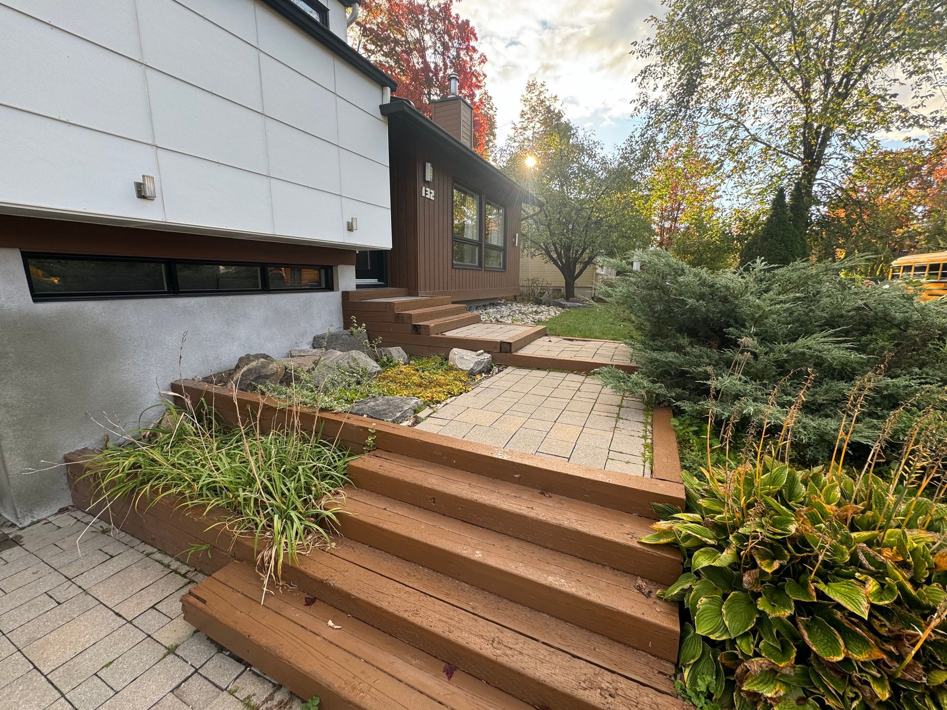 Une maison avec des escaliers qui y mènent et un bus scolaire jaune en arrière-plan.
