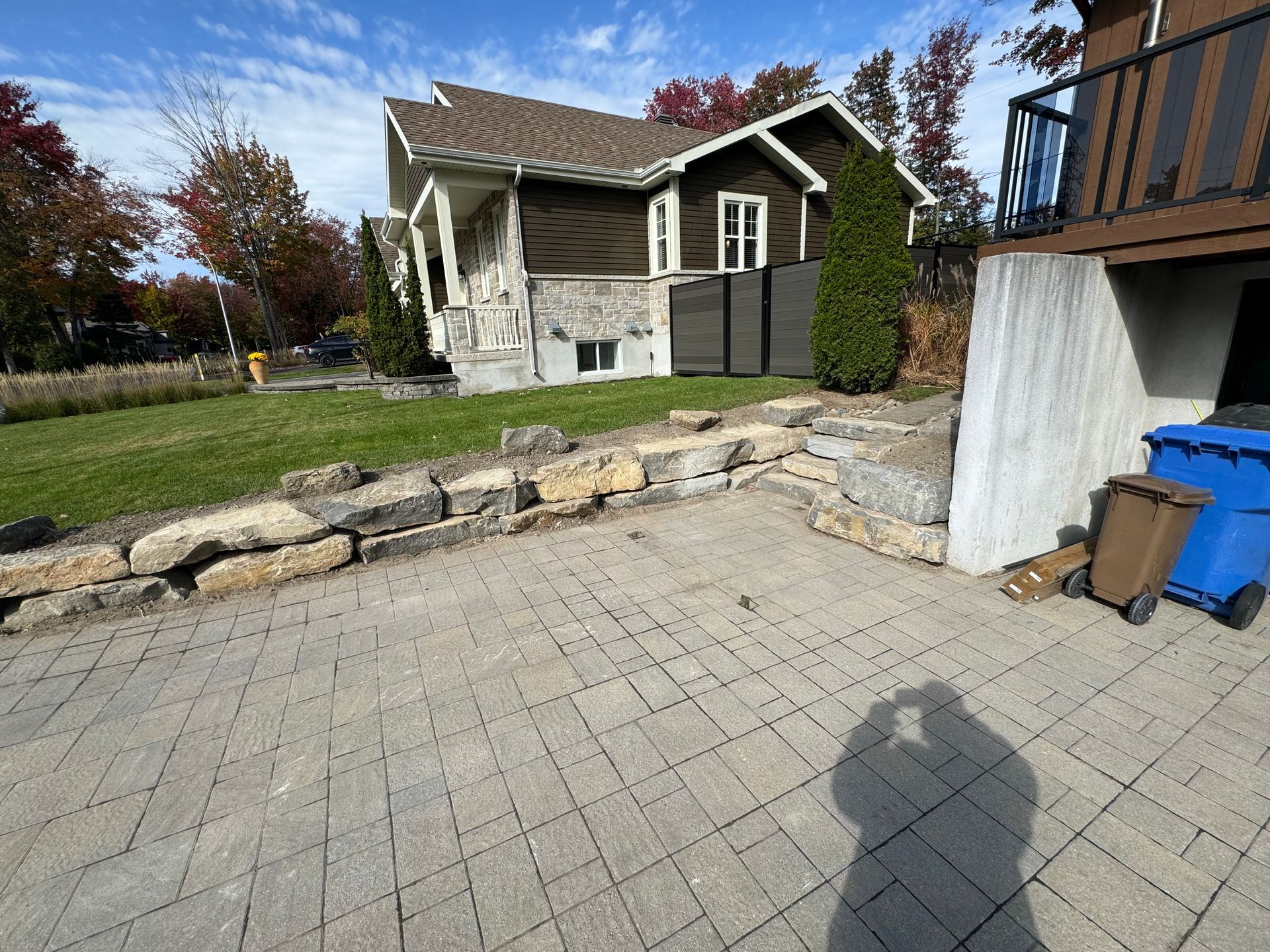 L'ombre d'une personne est projetée sur un patio en briques devant une maison.