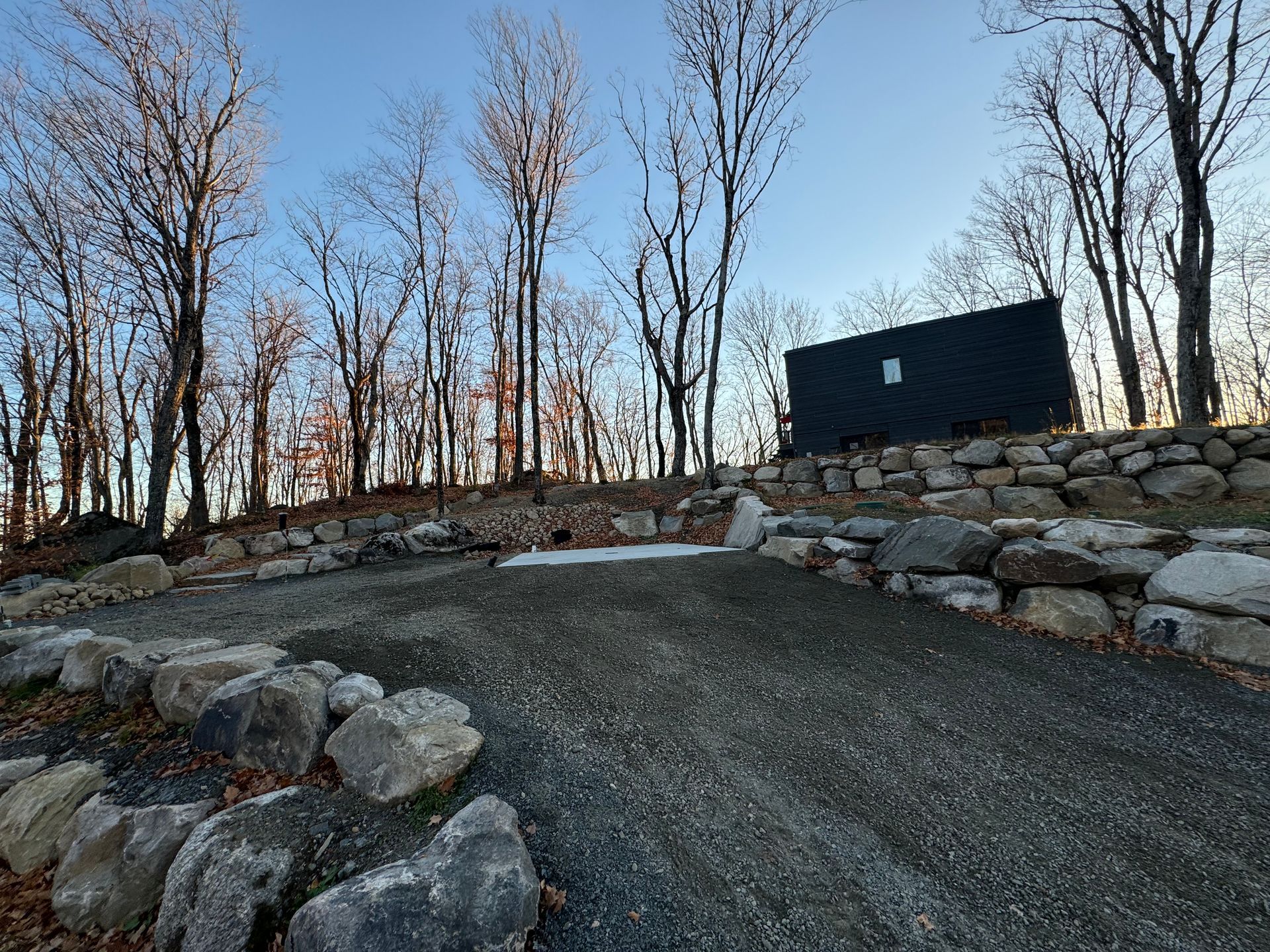 Un bâtiment noir est assis au sommet d'une colline rocheuse au milieu d'une forêt.
