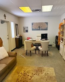 Office interior with a desk, chairs, couch, rug, and artwork.