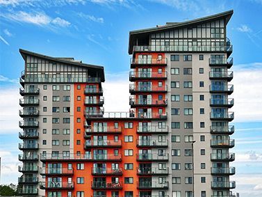 High-rise apartment buildings with gray and orange facades against a blue sky.