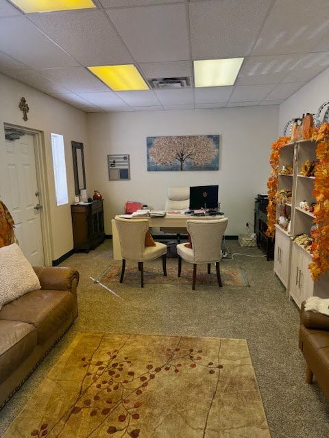 Office interior with desk, chairs, sofa, bookshelves, and rug; decorated for fall.