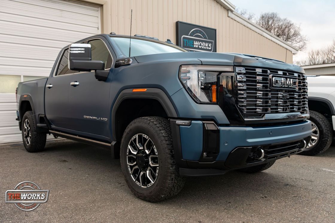 A blue pickup truck is parked in front of a garage door.