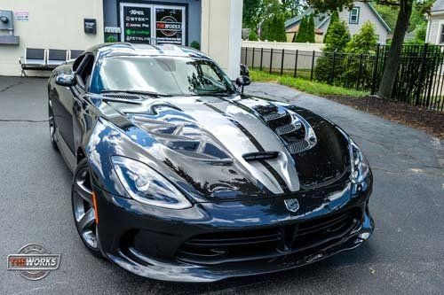 A black dodge viper is parked in front of a building.