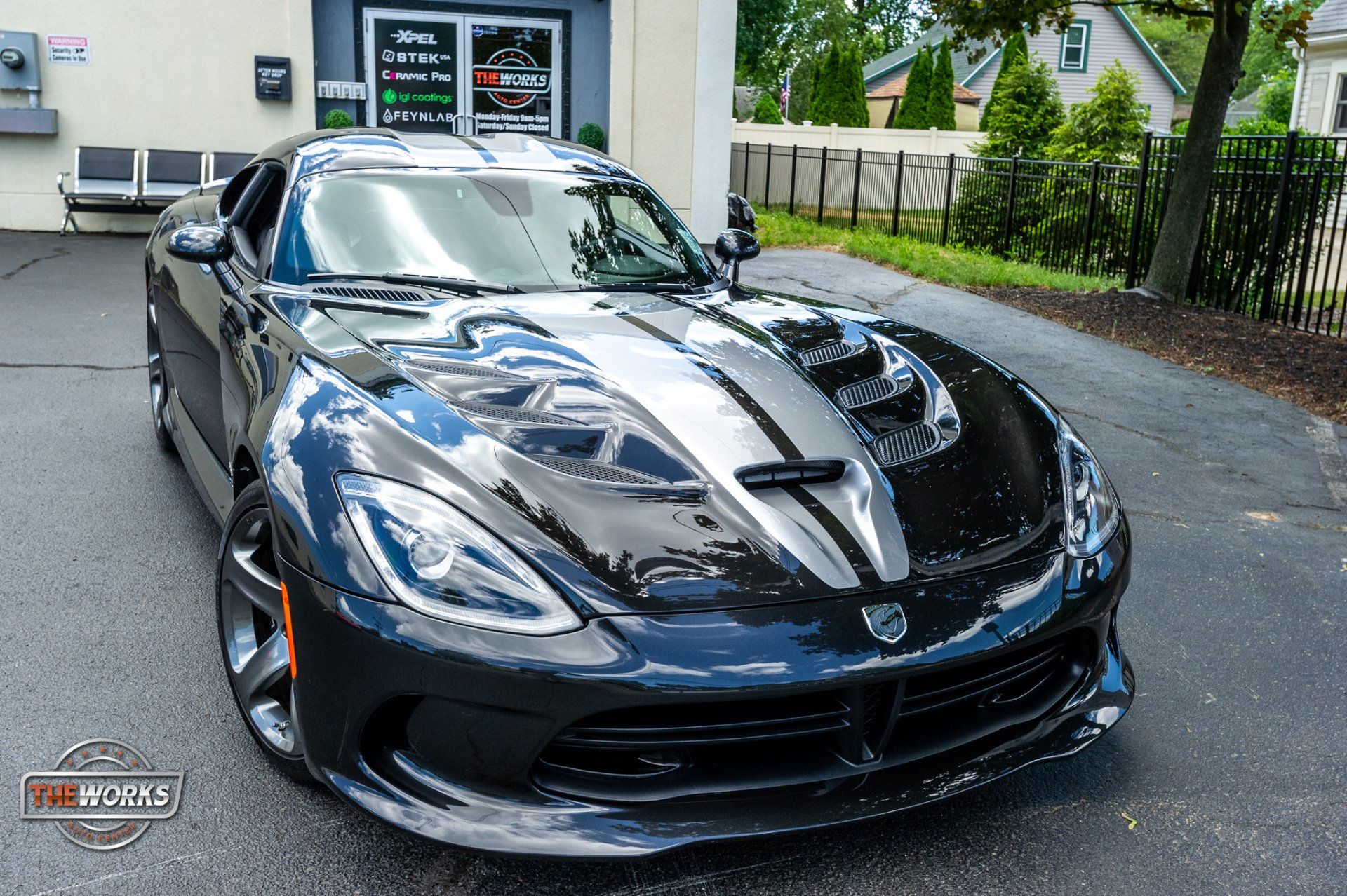 A black dodge viper is parked in front of a building