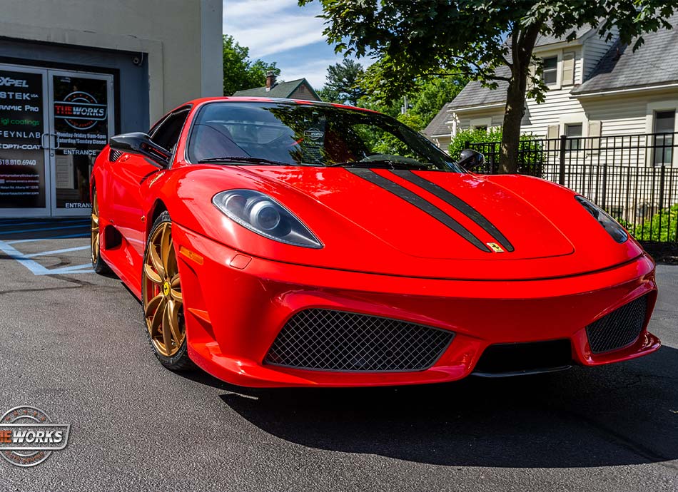 Red Ferrari sports car with gold rims parked in front of a building.