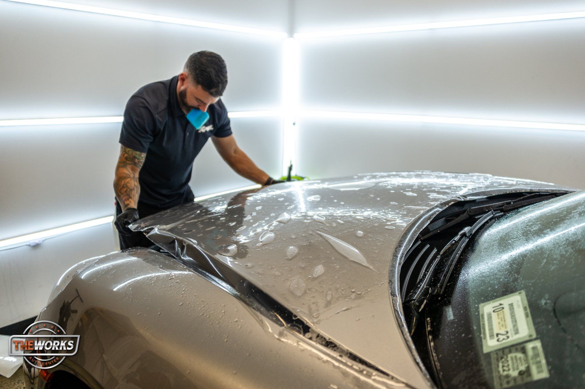 man applying ppf to car's hood