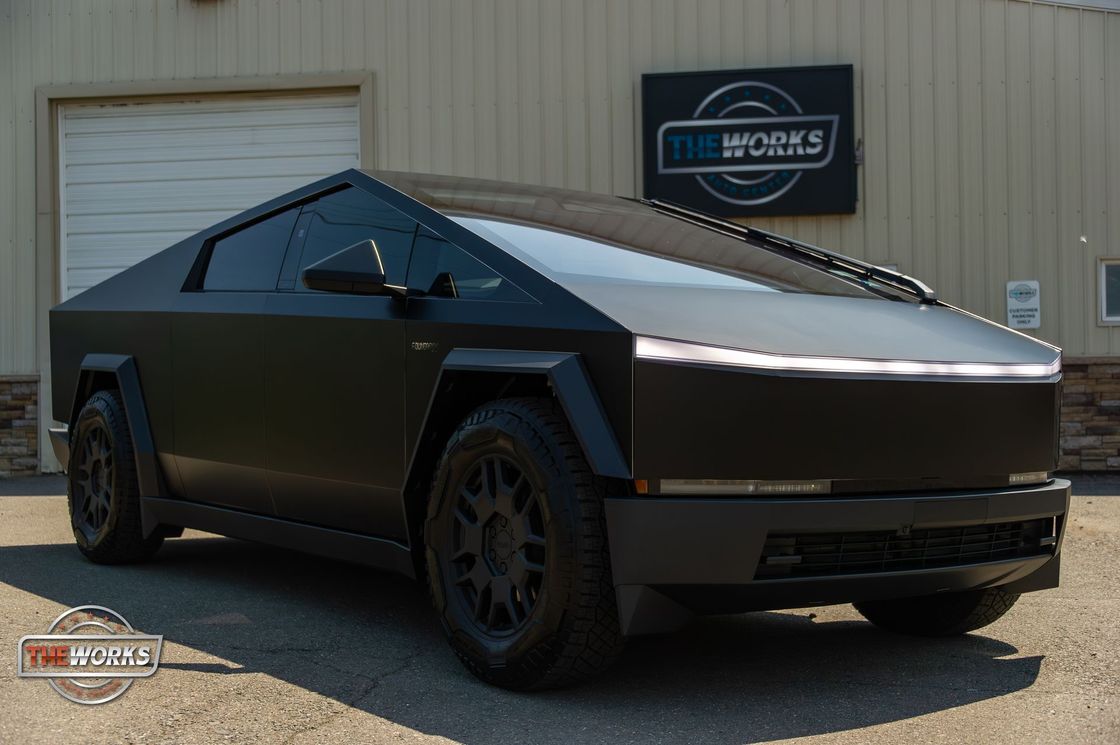 A black tesla cybertruck is parked in front of a building.