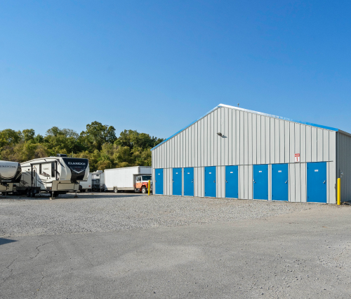 Storage units with blue doors, parked RVs, and a clear blue sky.