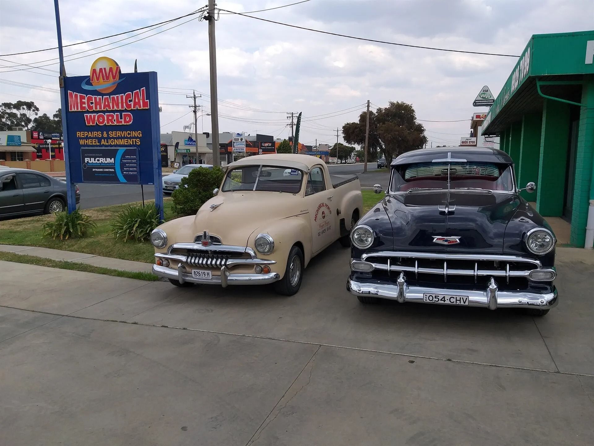 Two classic cars parked next to a mechanic sign — Mechanical World In Wagga Wagga, NSW