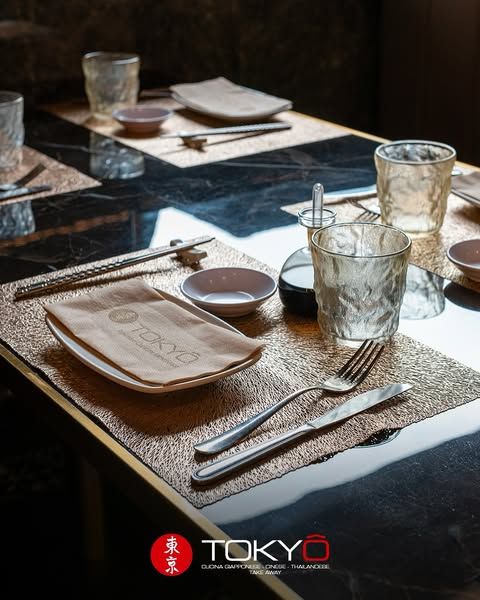 Apparecchiatura del tavolo del ristorante con tovaglietta, bacchette e bicchieri dorati. Logo