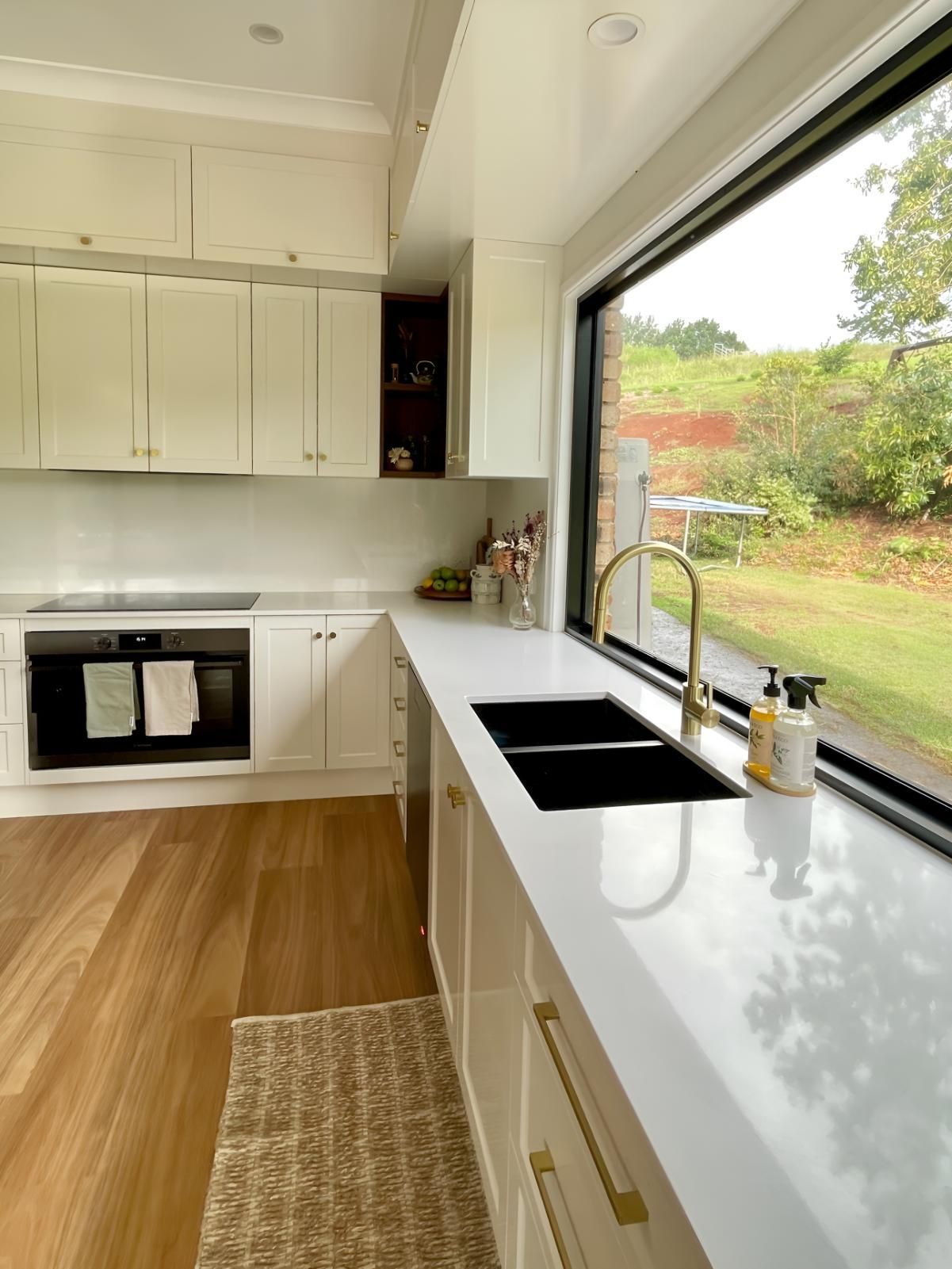 A Kitchen With White Cabinets, a Sink, and a Large Window 