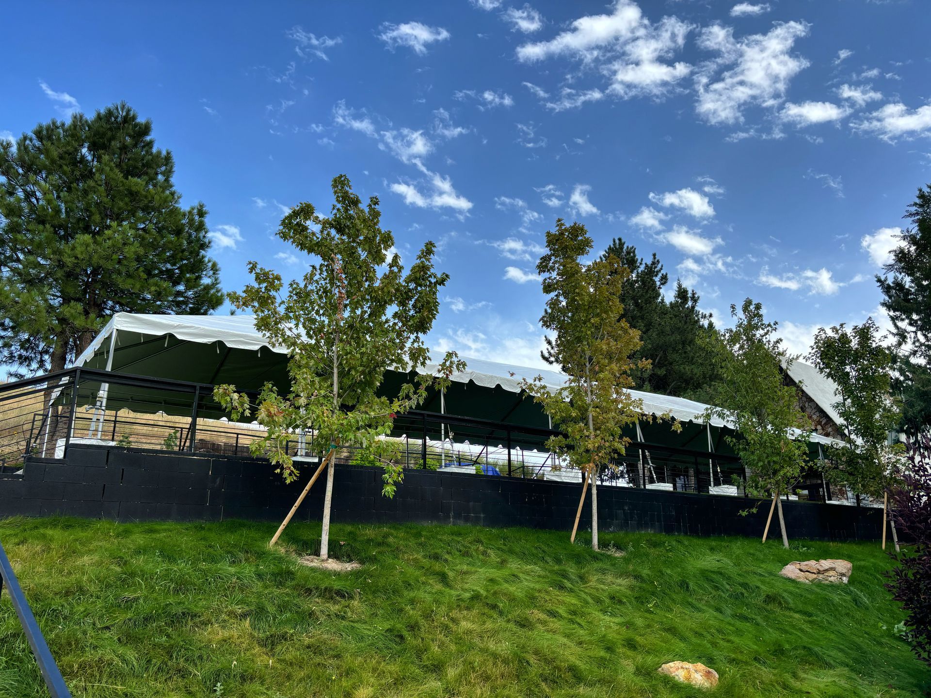 A large white tent is sitting on top of a grassy hill.