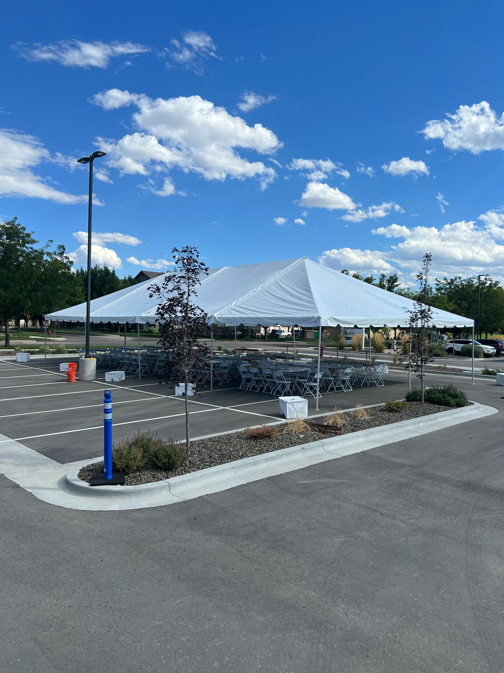 A large white tent is sitting in the middle of a parking lot.
