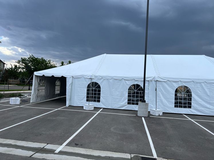 A large white tent is sitting in a parking lot.