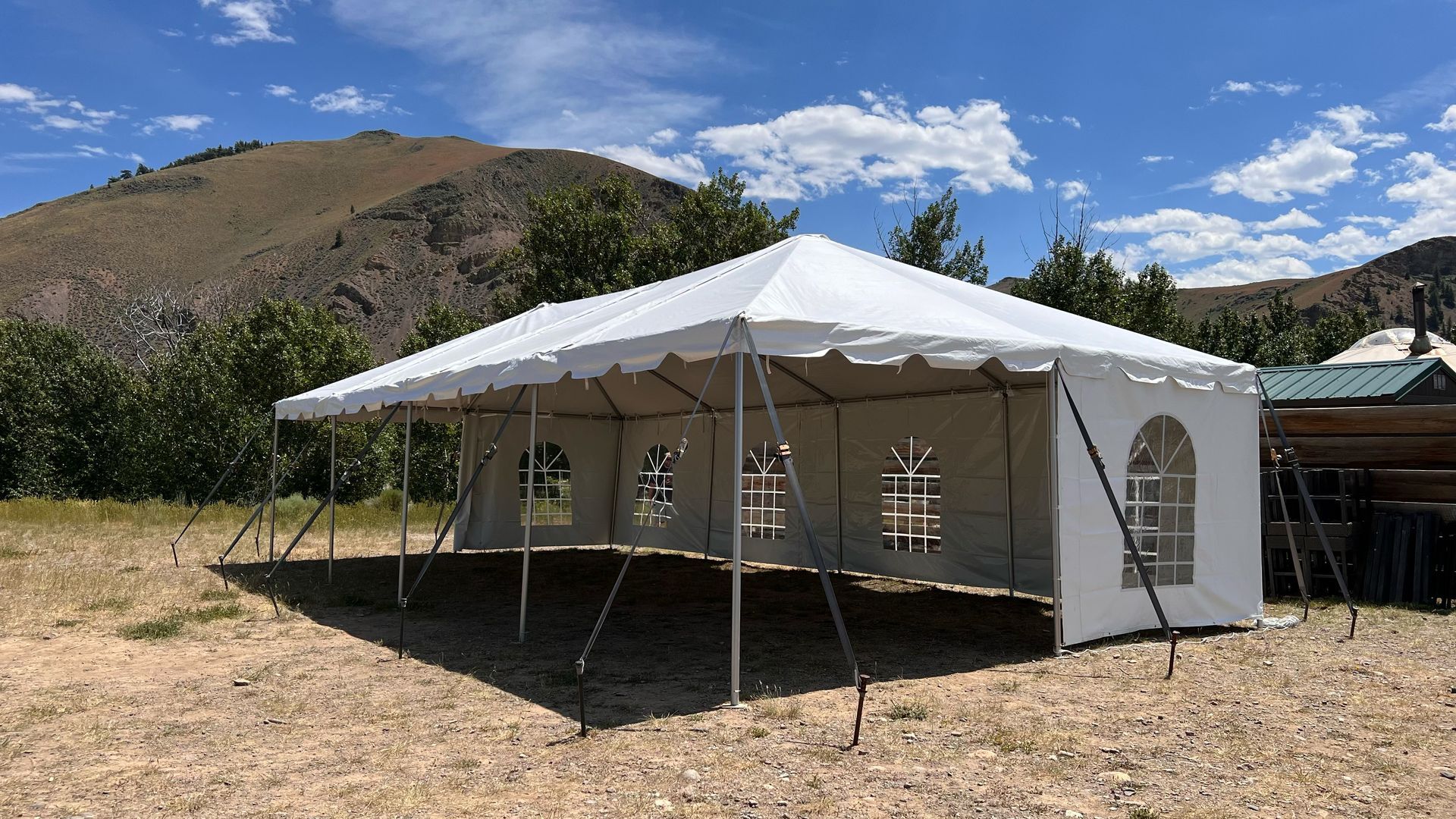A large white tent is sitting in the middle of a dirt field.
