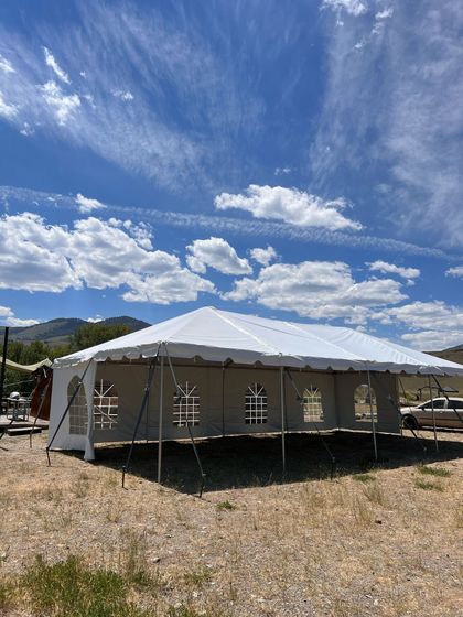 A large white tent is sitting in the middle of a dirt field.