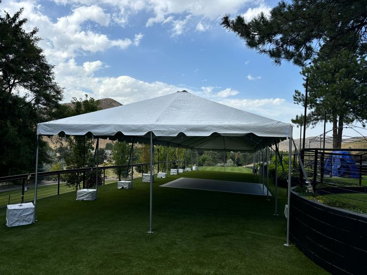 A large white tent is sitting on top of a lush green field.