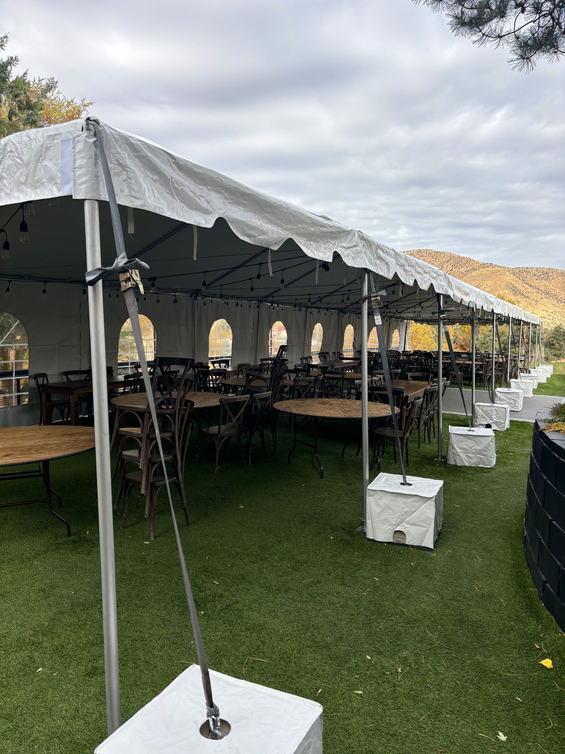 A large tent with tables and chairs is sitting on top of a lush green field.