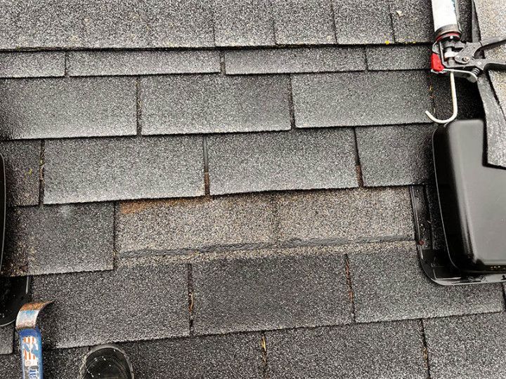 A close up of a roof with shingles and tools on it.