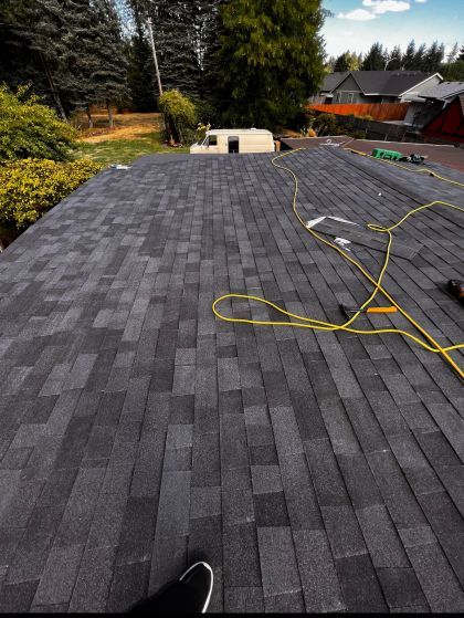 A person is standing on a roof with a yellow cord hanging from it.