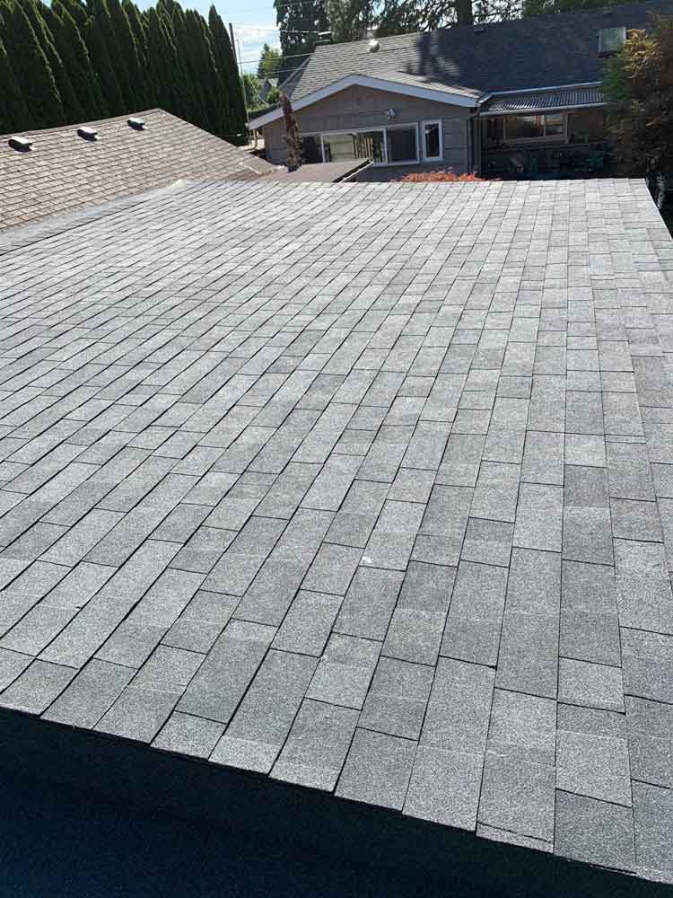 A roof with a lot of shingles on it and a house in the background.