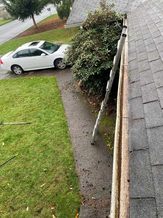 A white car is parked on the side of the road next to a gutter.