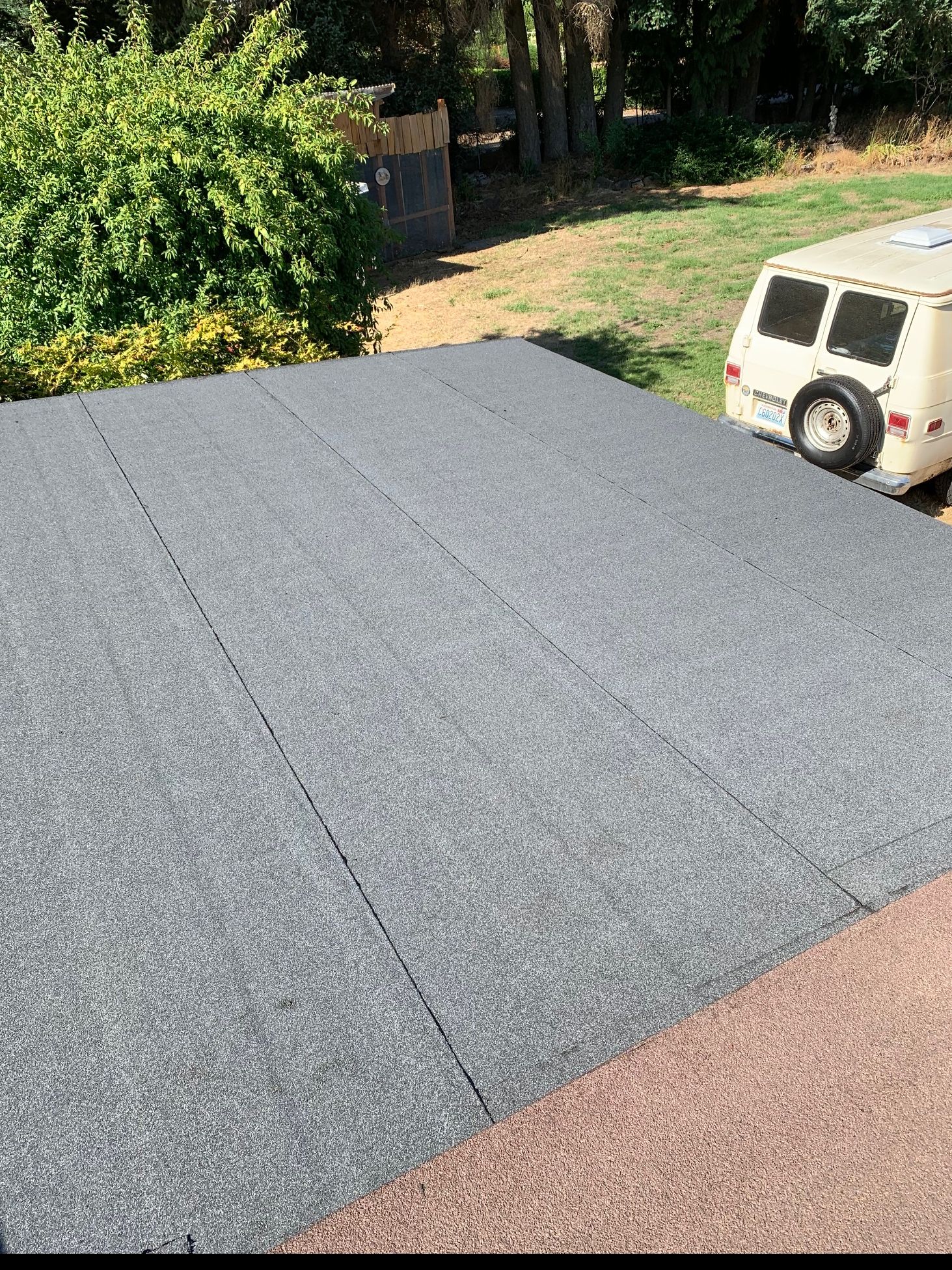 A white van is parked on top of a concrete driveway.